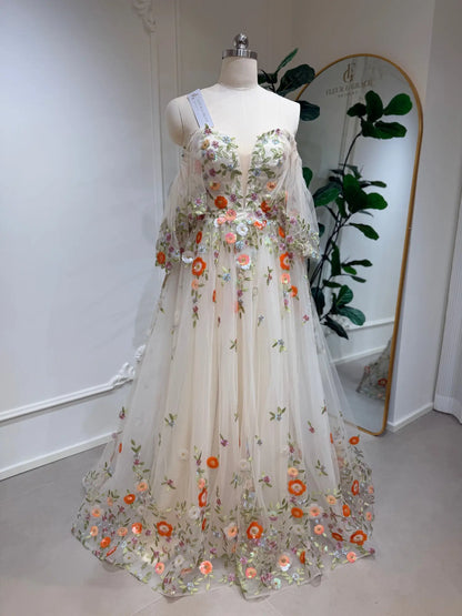 Whimsical A-line wedding dress featuring colorful floral embroidery on sheer tulle with romantic angel sleeves.