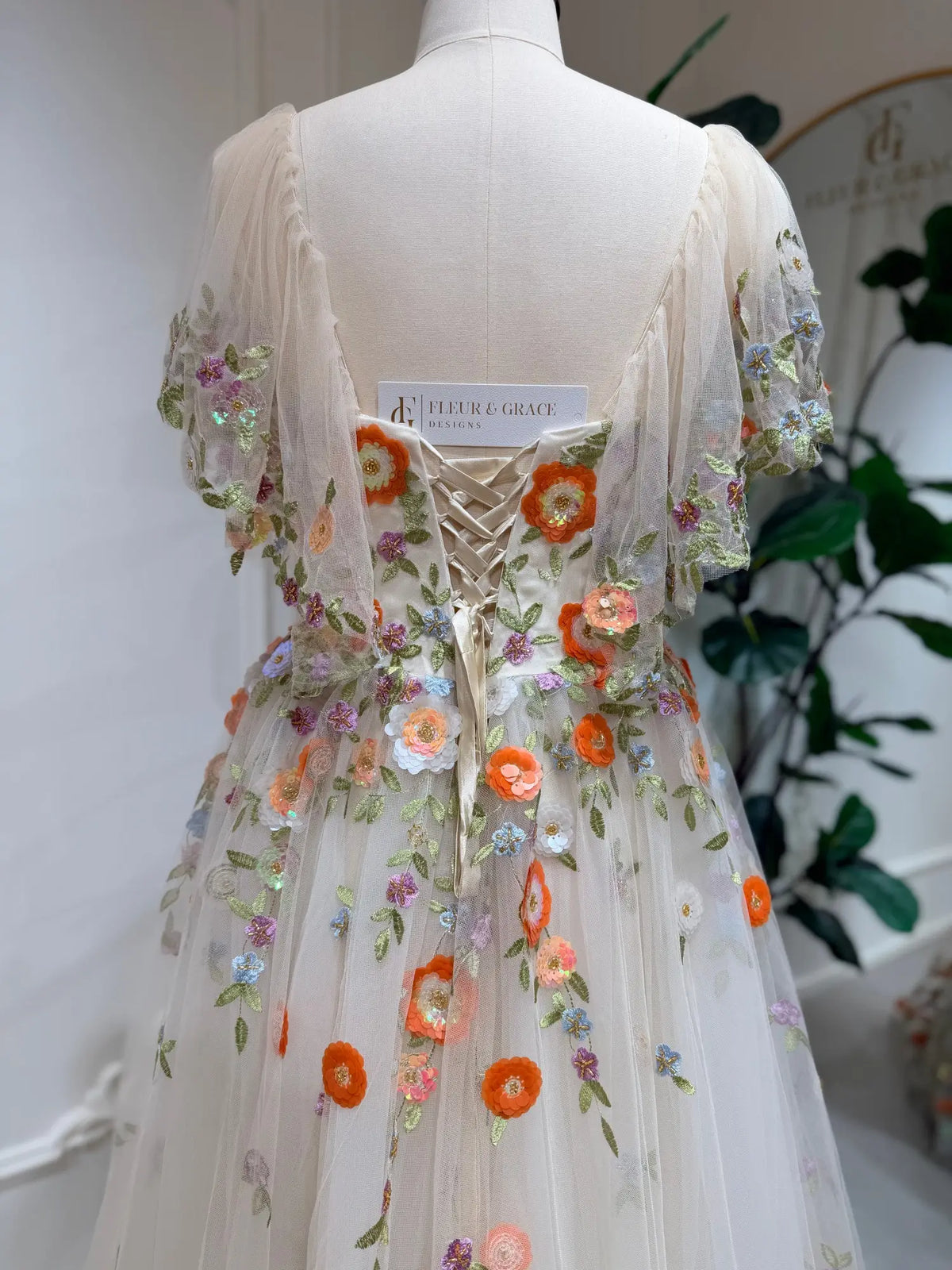 Whimsical wedding dress with multicolor floral embroidery, sheer angel sleeves, and an adjustable corset lace-up back.