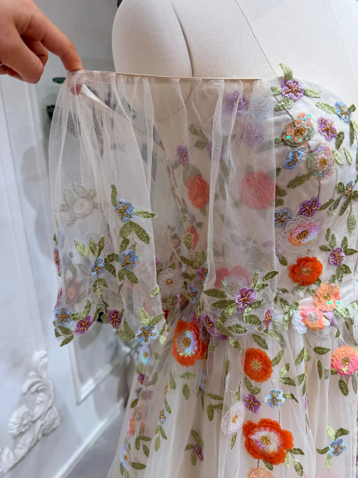 Raya wedding dress featuring sheer tulle, angel sleeves, and vibrant multicolor floral embroidery with sequin details.