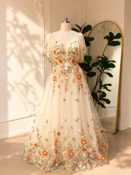 Whimsical A-line wedding dress in sheer tulle with vibrant multicolor floral embroidery and romantic angel sleeves.