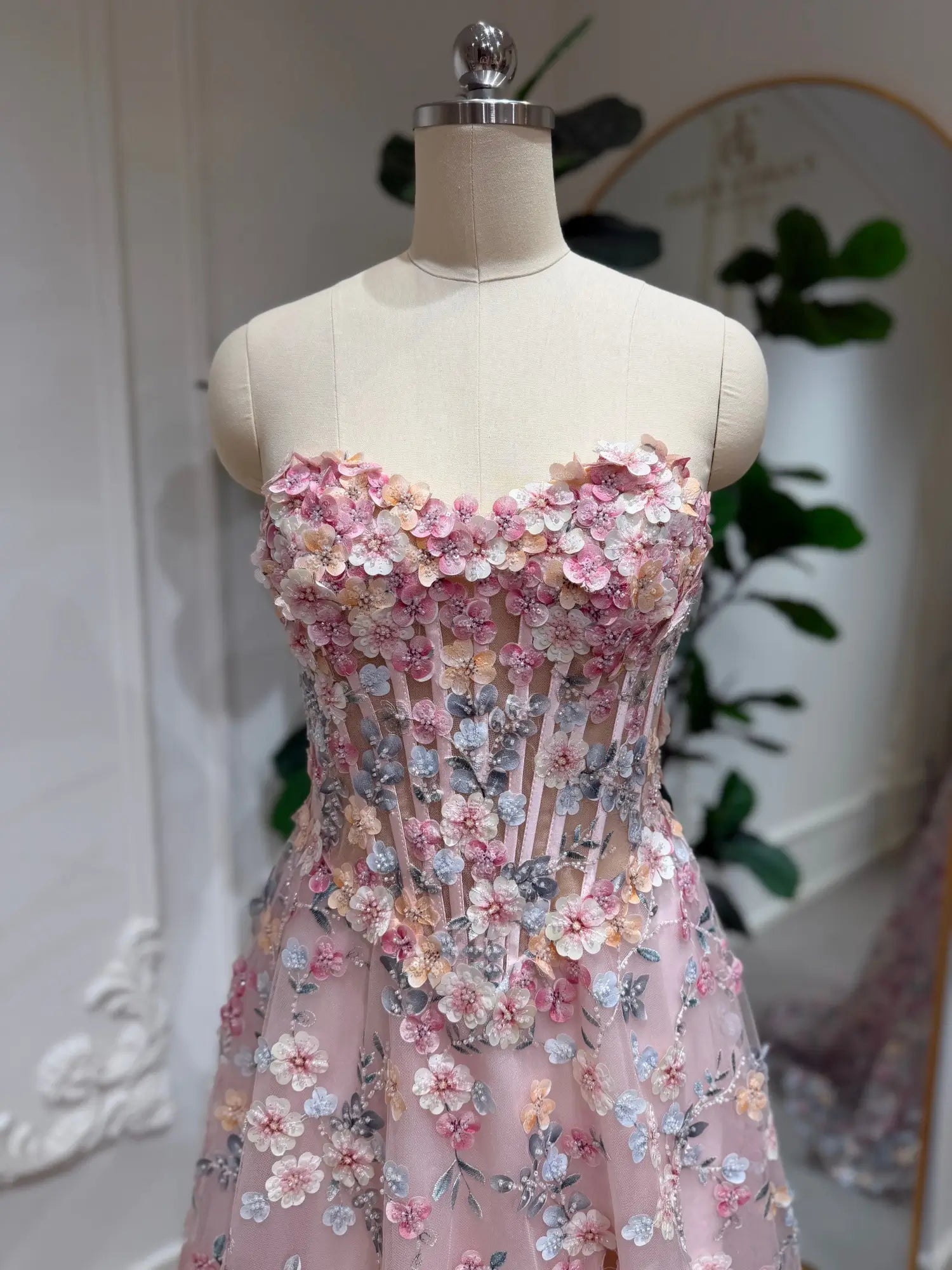 Blush pink tulle prom dress featuring a structured corset bodice with intricate 3D floral embroidery and a strapless neckline.