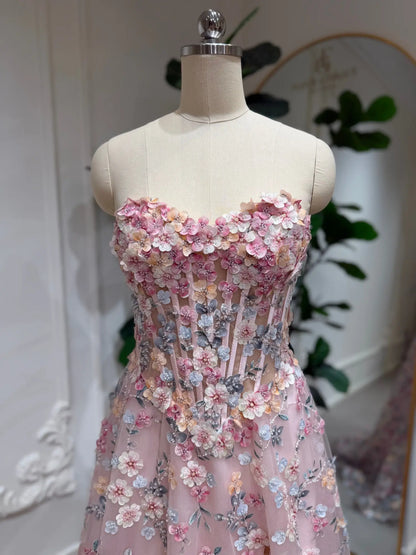 Blush pink tulle prom dress featuring a structured corset bodice with intricate 3D floral embroidery and a strapless neckline.