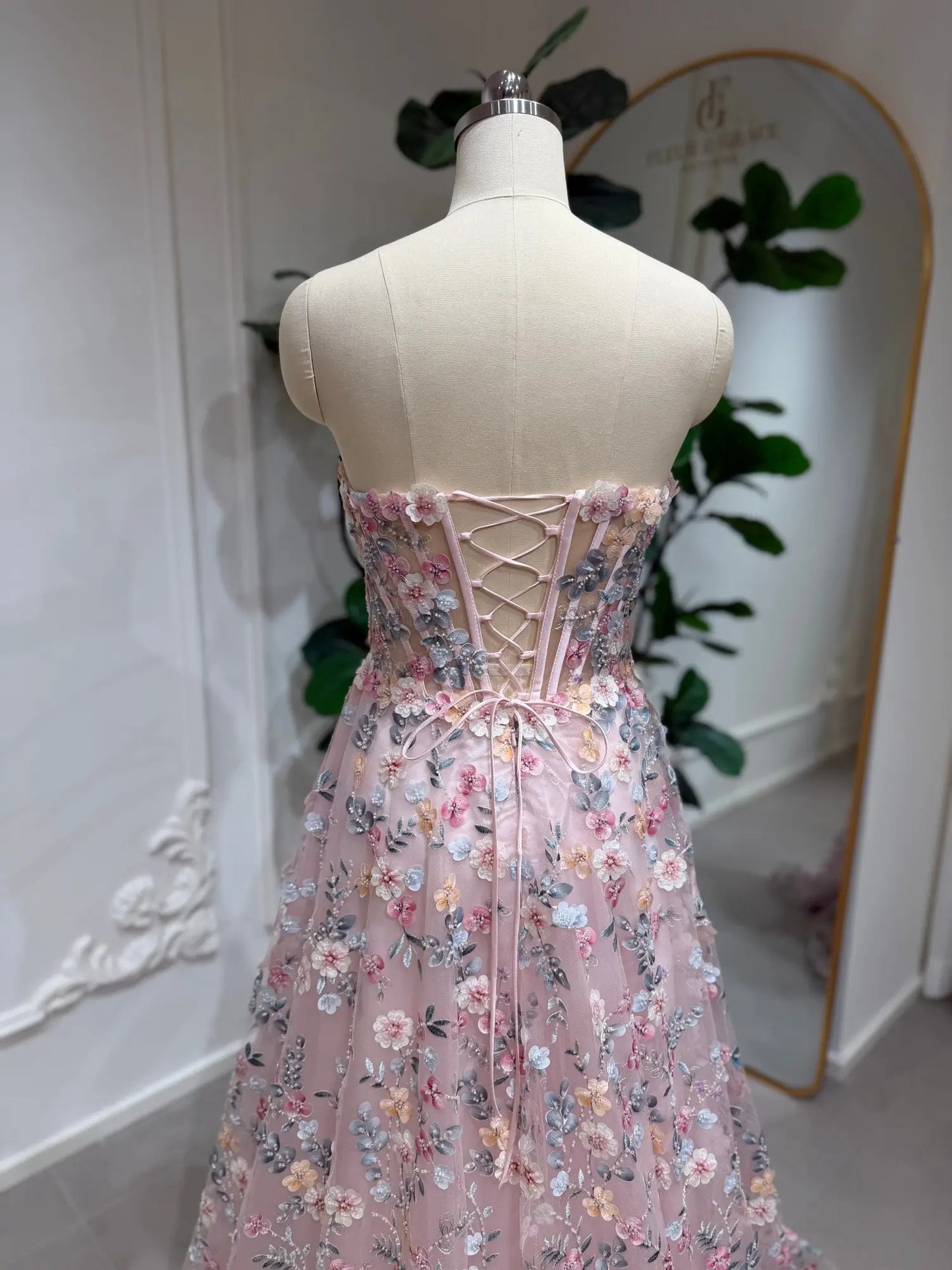 Blush pink floral embroidered prom dress featuring a strapless corset bodice and romantic lace-up back closure.