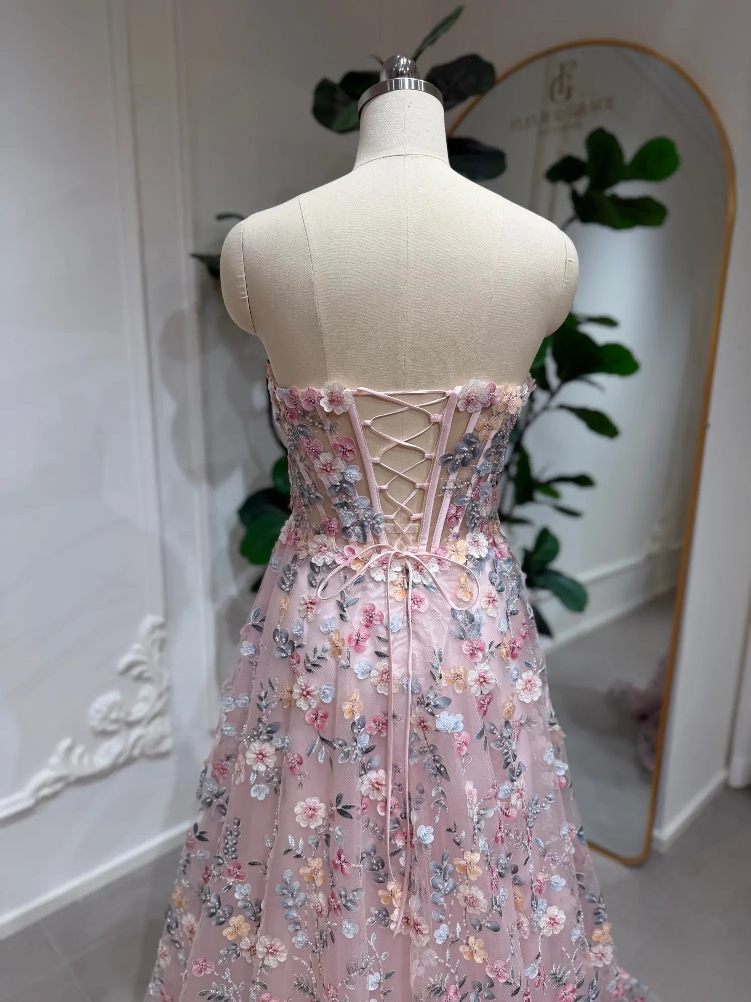 Blush pink floral embroidered prom dress featuring a strapless corset bodice and romantic lace-up back closure.