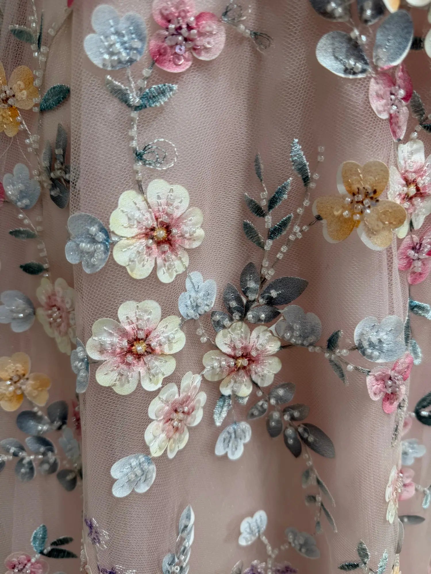 Blush pink tulle prom dress featuring intricate floral embroidery and delicate beadwork for a romantic, garden-inspired look.