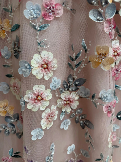 Blush pink tulle prom dress featuring intricate floral embroidery and delicate beadwork for a romantic, garden-inspired look.