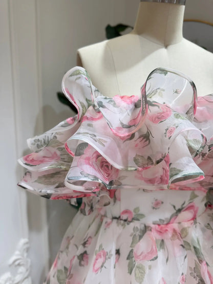 Off-the-shoulder pink floral organza gown with a dramatic tiered ruffle neckline on a dress form.