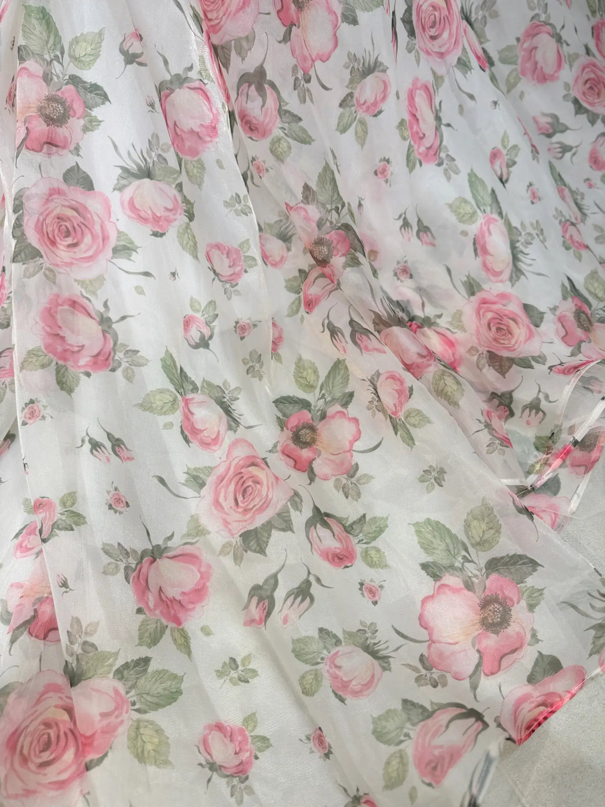 Sheer white organza fabric featuring a romantic pink floral rose print with green leaves for a fairy tale gown.