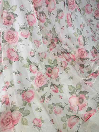 Sheer white organza fabric featuring a romantic pink floral rose print with green leaves for a fairy tale gown.