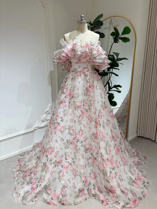 Rosie-pink floral organza wedding gown with an off-the-shoulder tiered ruffle neckline and a flowing A-line skirt.