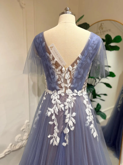 Dusty blue A-line wedding dress with off-white floral lace, illusion V-back, and romantic flutter sleeves on a mannequin.