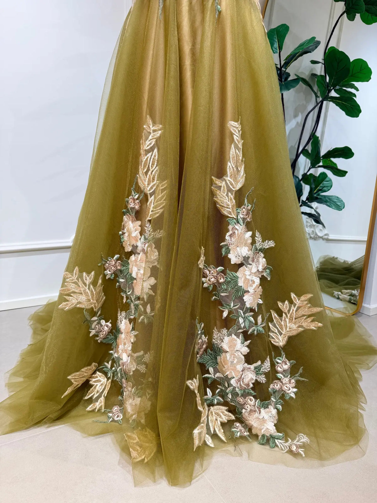 Olive green tulle wedding dress featuring delicate floral embroidery and a dramatic, flowing chapel-length train.