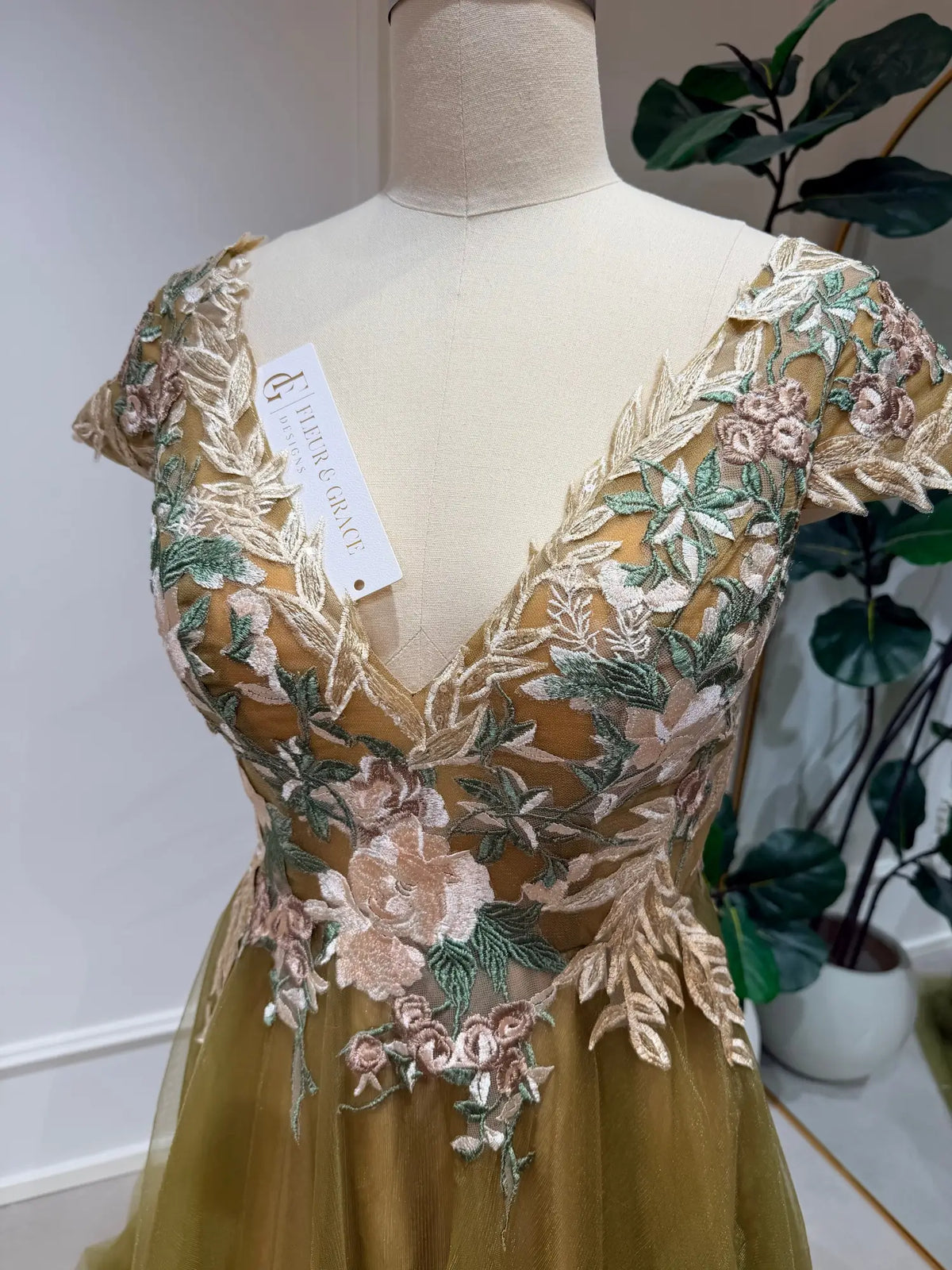 Olive green wedding dress featuring a V-neck bodice with intricate floral embroidery and delicate tulle sleeves.