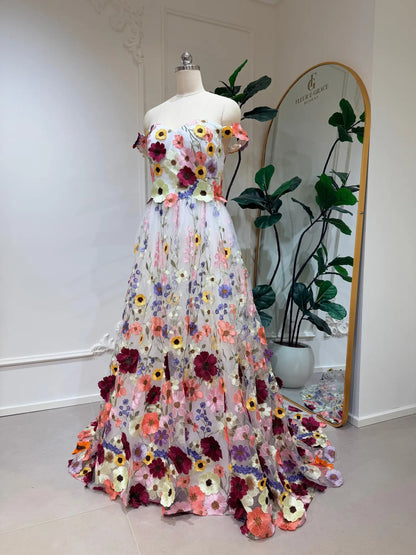 Off-shoulder ivory wedding dress with vibrant, colorful floral embroidery on a flowing A-line tulle skirt.