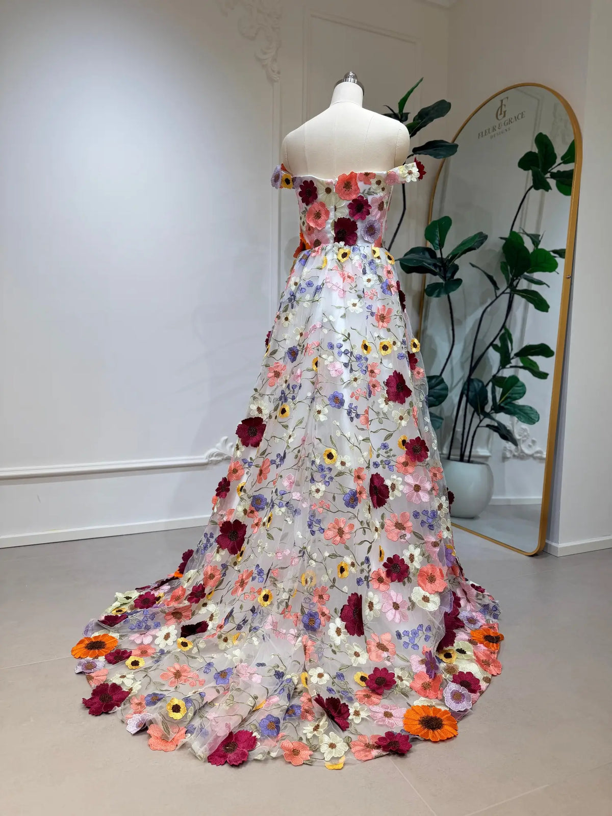Ivory tulle wedding dress with vibrant, colorful floral embroidery, off-shoulder sleeves, and a flowing A-line skirt.