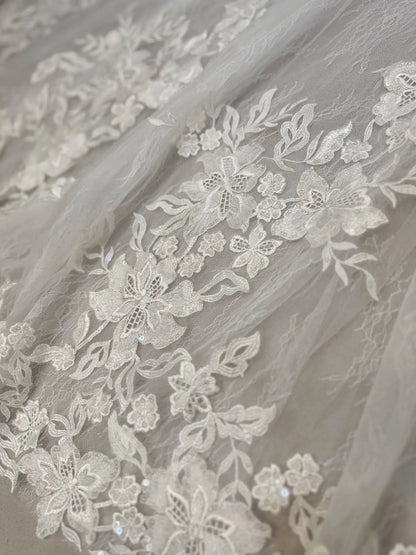Ivory floral lace appliqués with delicate sequins layered over soft nude tulle on the Selin mermaid wedding dress.