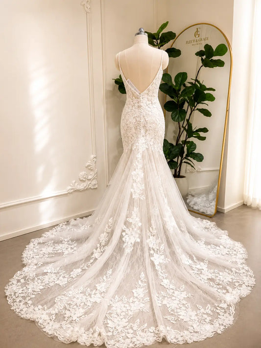 Ivory mermaid wedding dress with floral lace appliqués, low V-back, and a dramatic chapel-length tulle train.