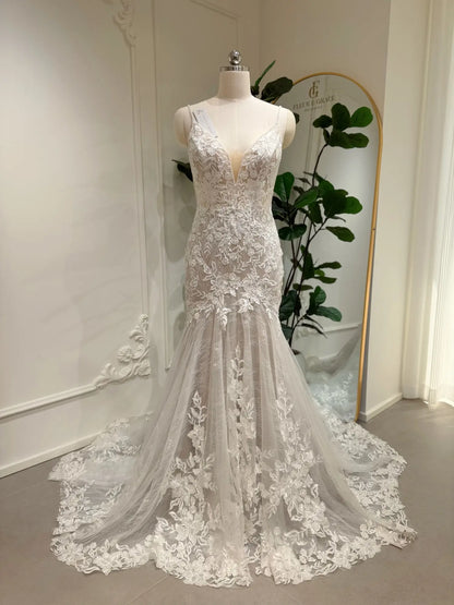 Ivory mermaid wedding dress with floral lace appliqués, deep V-neckline, and nude lining on a bridal mannequin.