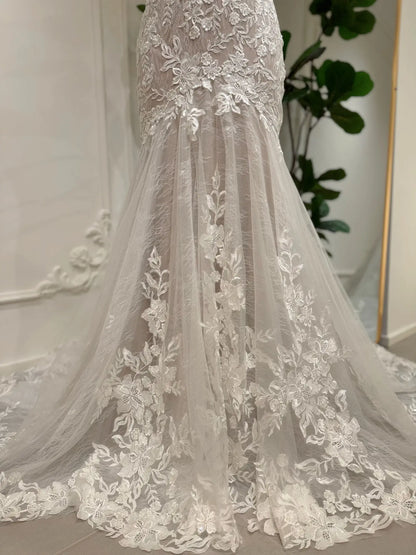 Selin mermaid wedding dress featuring ivory floral lace appliqués over a nude lining and a dramatic tulle train.