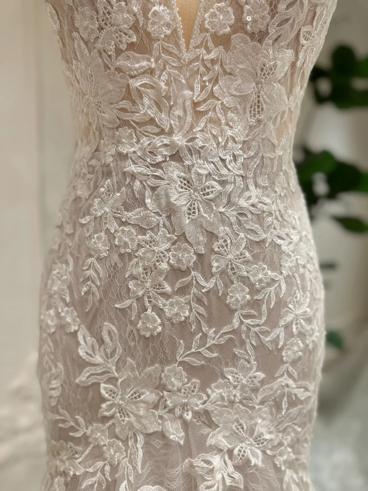 Ivory mermaid wedding dress featuring intricate floral lace appliqués over a soft nude lining for a romantic look.