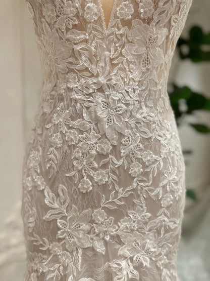 Ivory mermaid wedding dress featuring intricate floral lace appliqués over a soft nude lining for a romantic look.