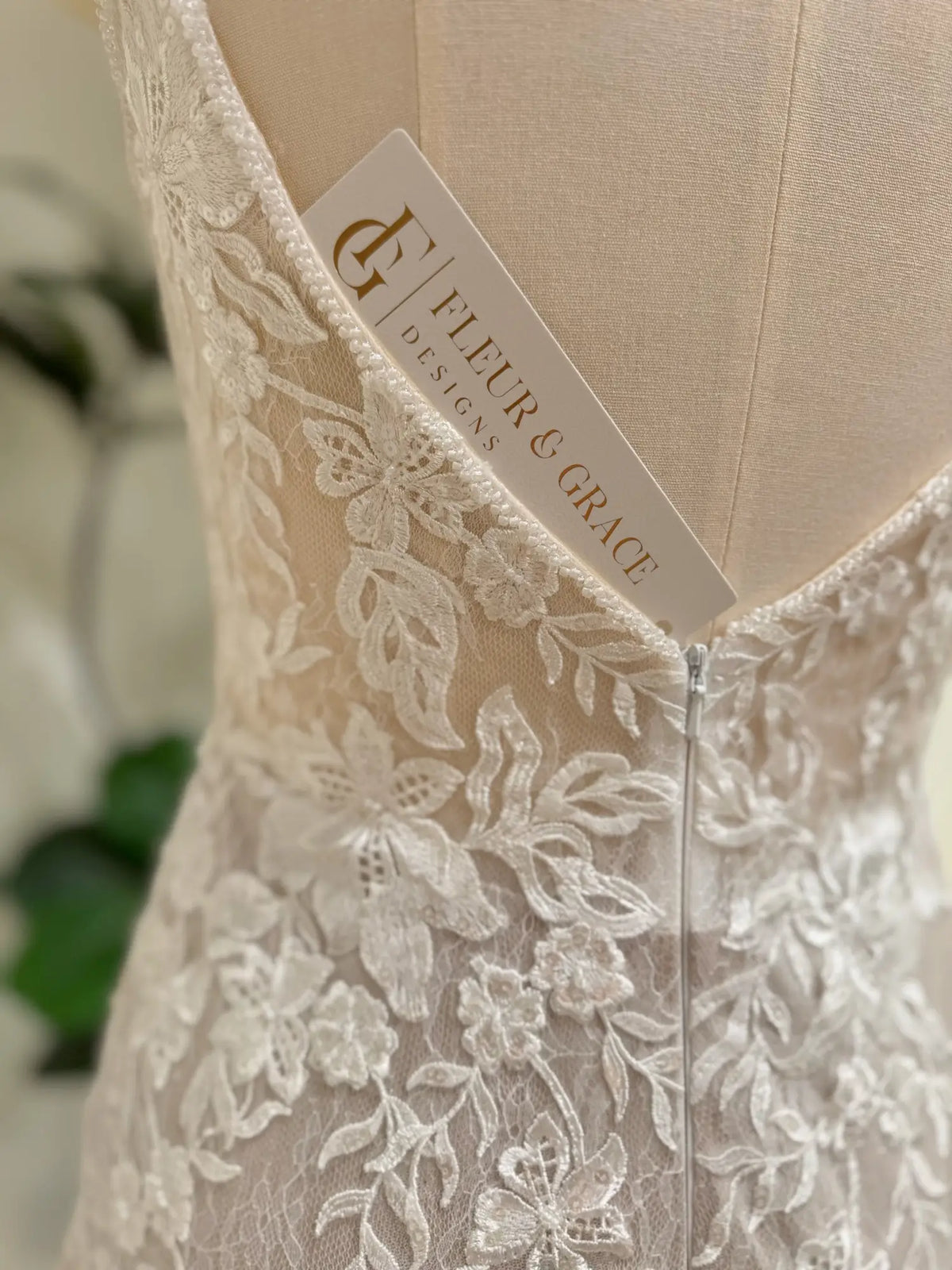 Ivory floral lace mermaid wedding dress with a low V-back and nude lining by Fleur & Grace.
