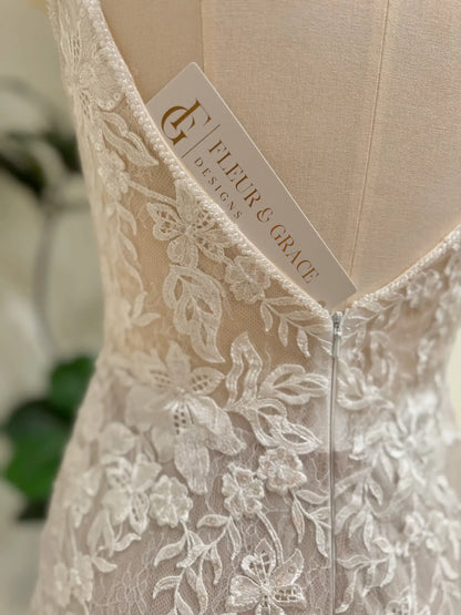 Ivory floral lace mermaid wedding dress with a low V-back and nude lining by Fleur & Grace.