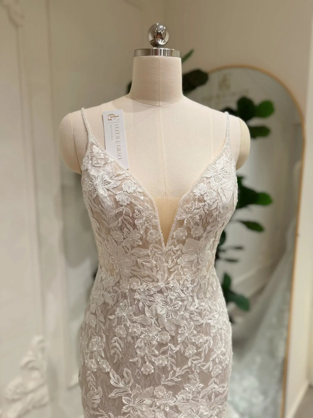 Ivory mermaid wedding dress featuring intricate floral lace appliqués, a deep V-neckline, and a flattering nude illusion bodice.