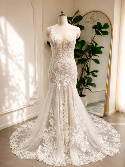 Ivory mermaid wedding dress with floral lace appliqués, deep V-neckline, and a dramatic chapel-length tulle train.