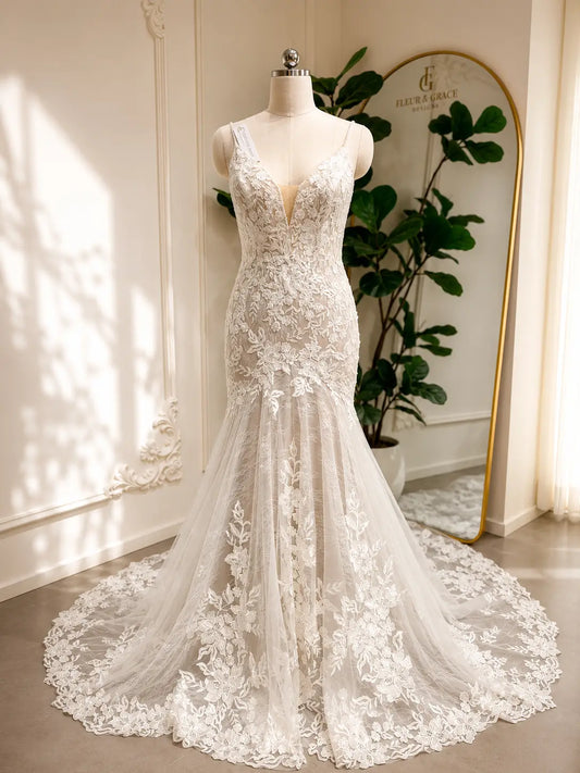 Ivory mermaid wedding dress with floral lace appliqués, deep V-neckline, and a dramatic chapel-length tulle train.