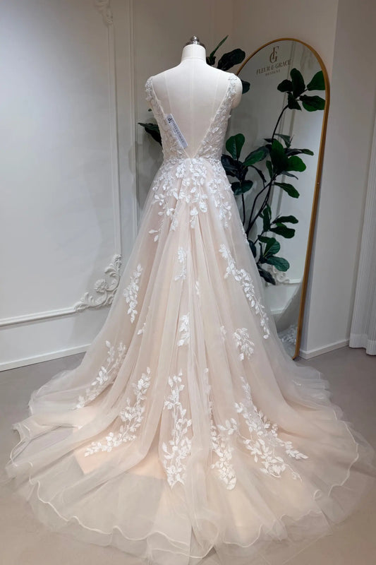 Champagne A-line wedding dress with floral lace appliqué, deep V-back, and flowing tulle skirt on a mannequin.