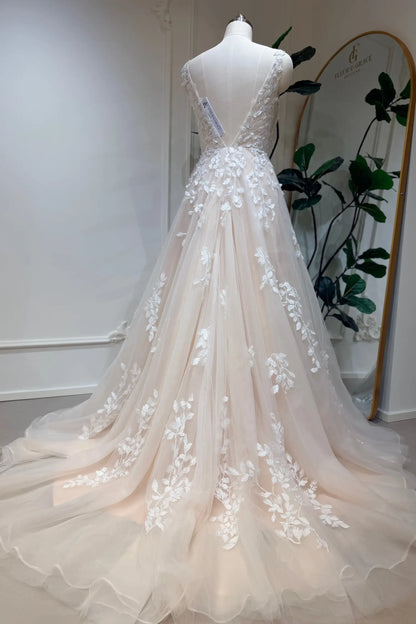 Champagne A-line wedding dress with floral lace appliqué, deep V-back, and flowing tulle train on a mannequin.