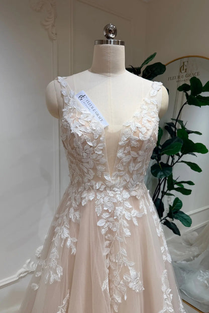 Champagne A-line wedding dress with a deep illusion V-neckline and intricate white floral lace appliqué on tulle.