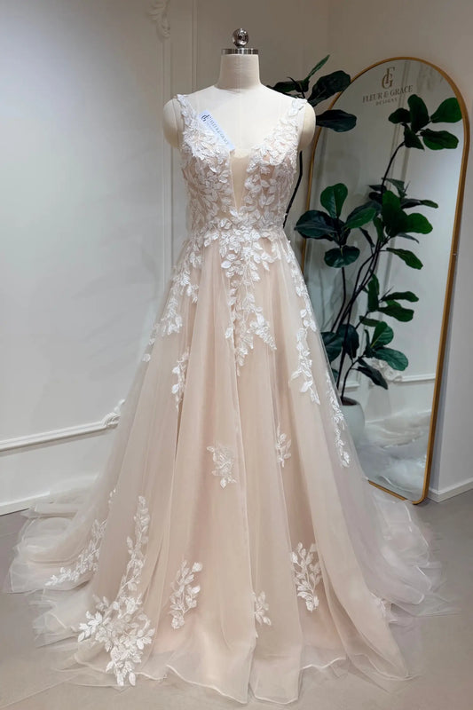 Champagne A-line wedding dress with floral lace appliqué, deep illusion V-neckline, and layered tulle skirt.
