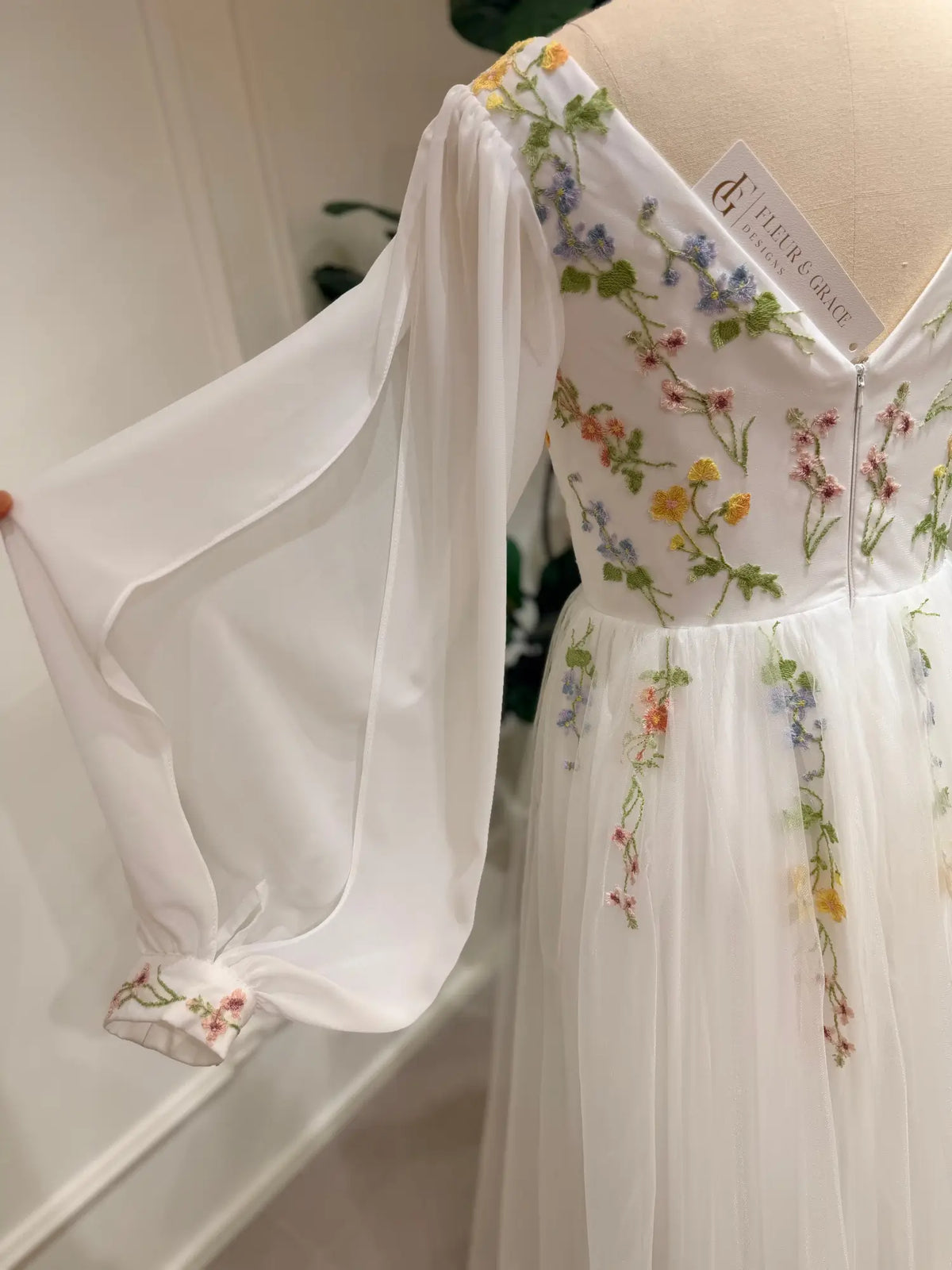 Stacey A-line wedding dress featuring pastel floral embroidery, sheer bishop sleeves, and a romantic tulle skirt.
