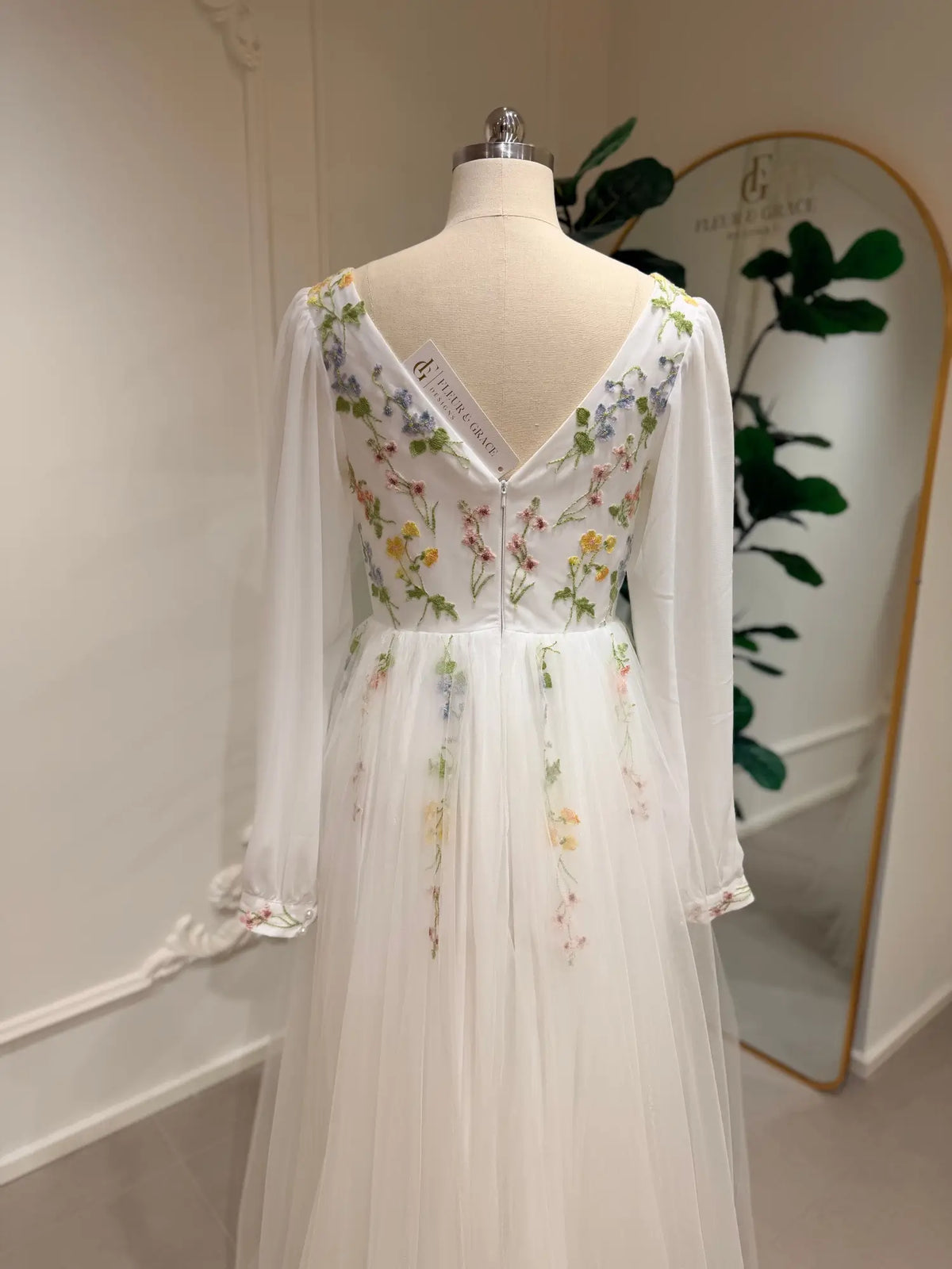 Stacey A-line wedding dress with pastel floral embroidery, sheer bishop sleeves, and a romantic V-back tulle skirt.