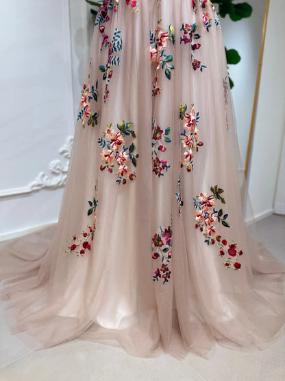 Blush tulle wedding dress featuring delicate multicolored floral embroidery and a flowing A-line skirt.