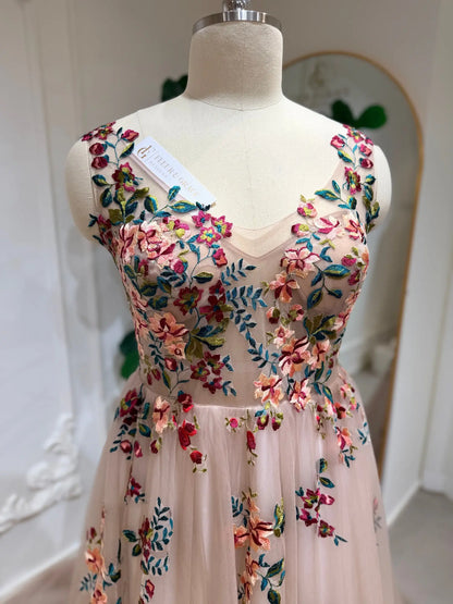 Blush tulle wedding dress featuring an illusion bodice with vibrant multicolored floral embroidery and a sweetheart neckline.