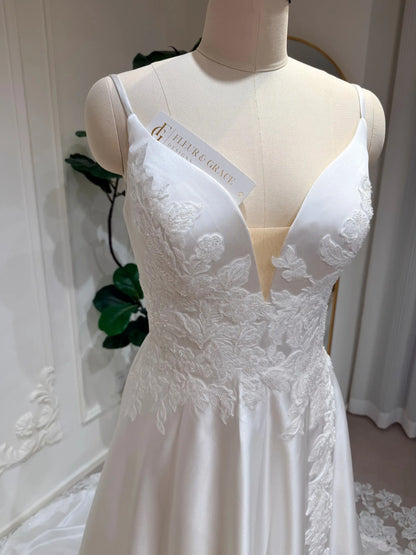 White satin A-line wedding dress with a deep V-neck, illusion bodice, and delicate floral lace appliqué.