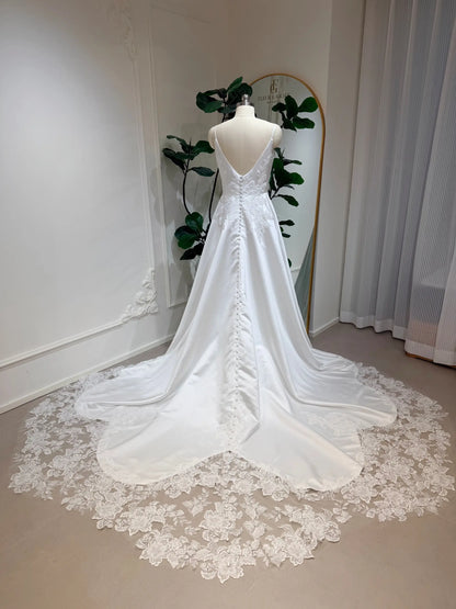 Satin A-line wedding dress with a deep V-back, button-up bodice, and a floral lace appliquéd cathedral train.