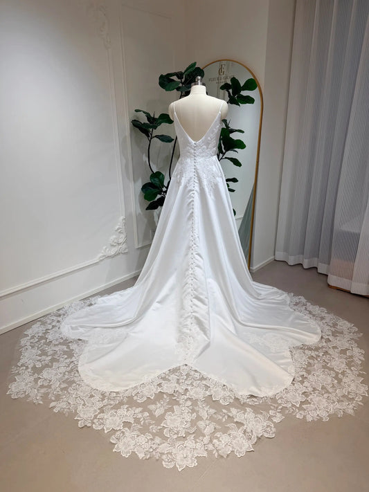 Satin A-line wedding dress with a deep V-back, button-up bodice, and a floral lace appliquéd cathedral train.