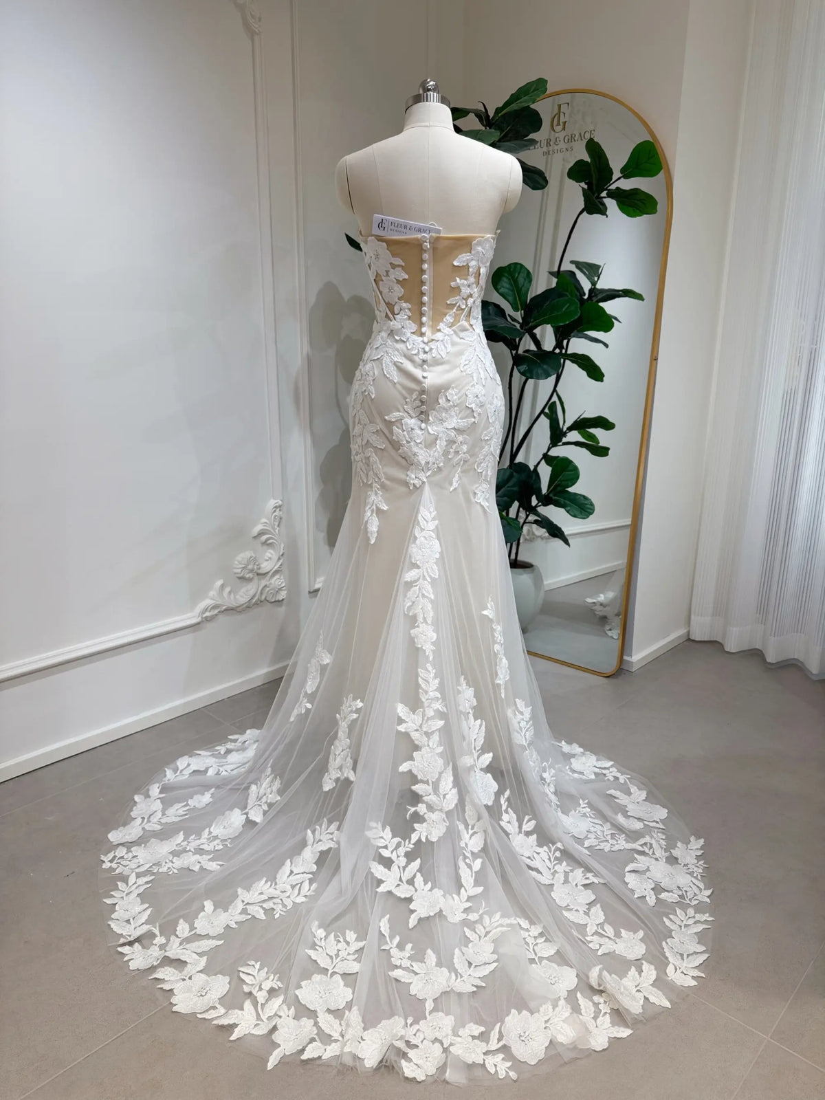 Back view of a strapless ivory lace mermaid wedding dress with a sheer boned bodice and court-length floral train.
