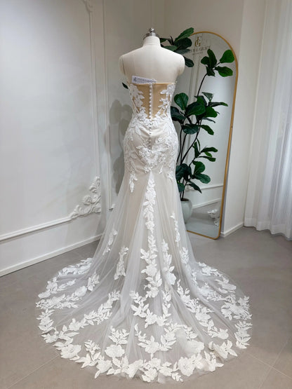 Back view of a strapless ivory lace mermaid wedding dress with a sheer boned bodice and court-length floral train.