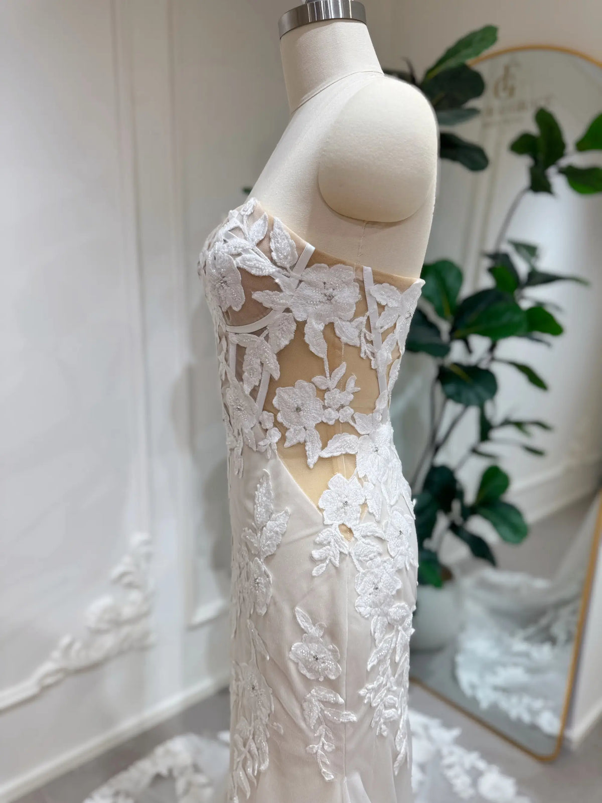 Strapless mermaid wedding dress with ivory floral lace, beaded details, and a sheer boned bodice on a beige lining.
