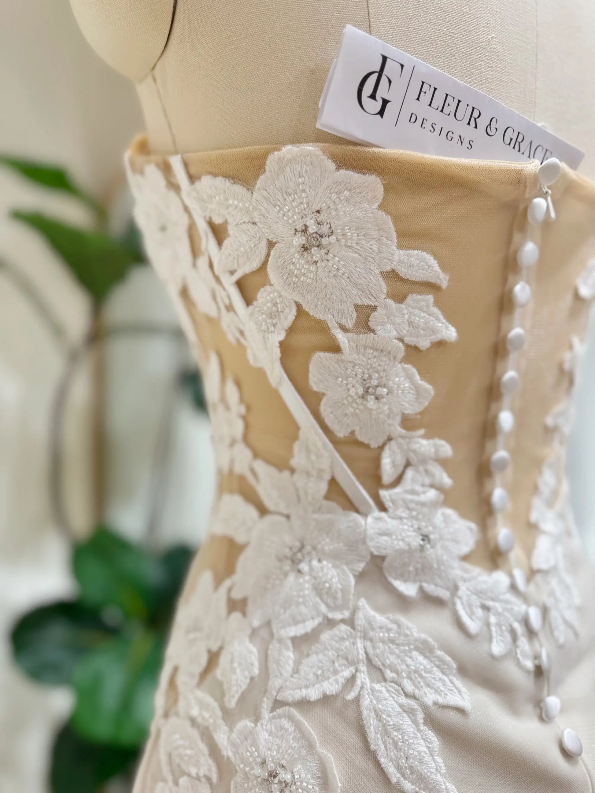 Tia Gown  by Fleur&Grace Designs — strapless mermaid wedding dress with basque waistline, sheer boned bodice, beige silk lining, ivory floral embroidery with beading, plunging V-neck, and court train.