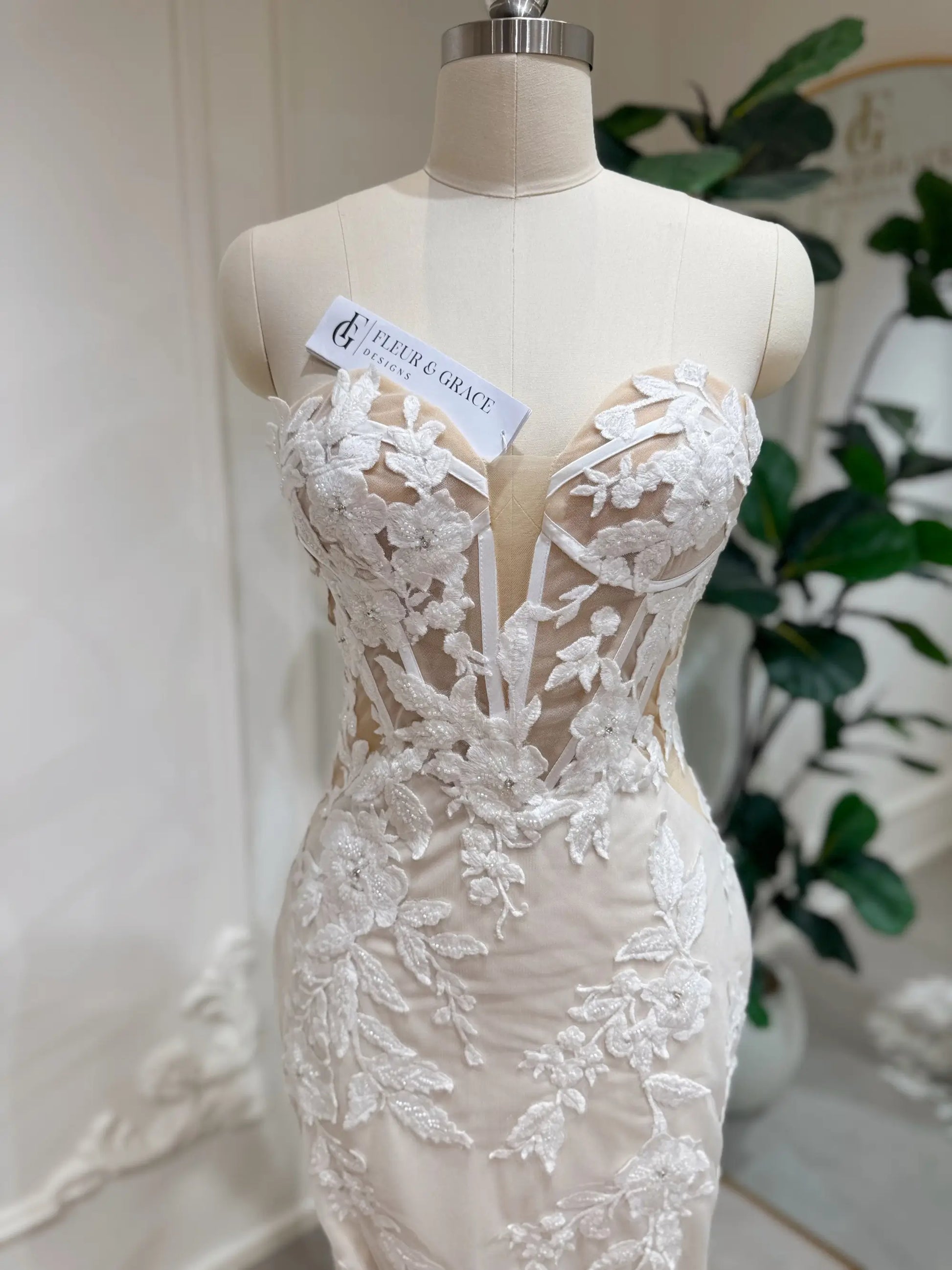 Tia Gown  by Fleur&Grace Designs — strapless mermaid wedding dress with basque waistline, sheer boned bodice, beige silk lining, ivory floral embroidery with beading, plunging V-neck, and court train.