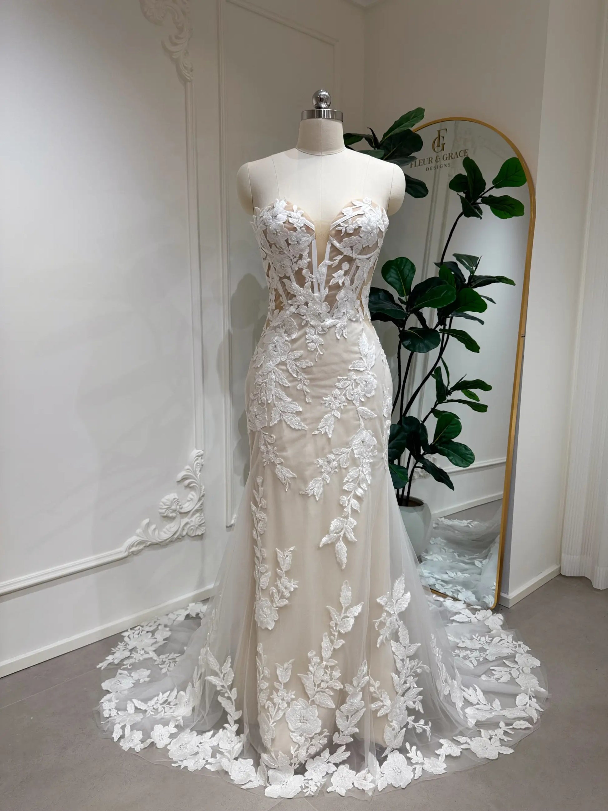 Tia Gown  by Fleur&Grace Designs — strapless mermaid wedding dress with basque waistline, sheer boned bodice, beige silk lining, ivory floral embroidery with beading, plunging V-neck, and court train.