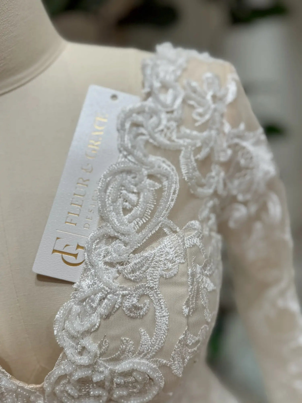 Close-up of Vera wedding dress featuring intricate white beaded lace embroidery over a soft nude illusion bodice.