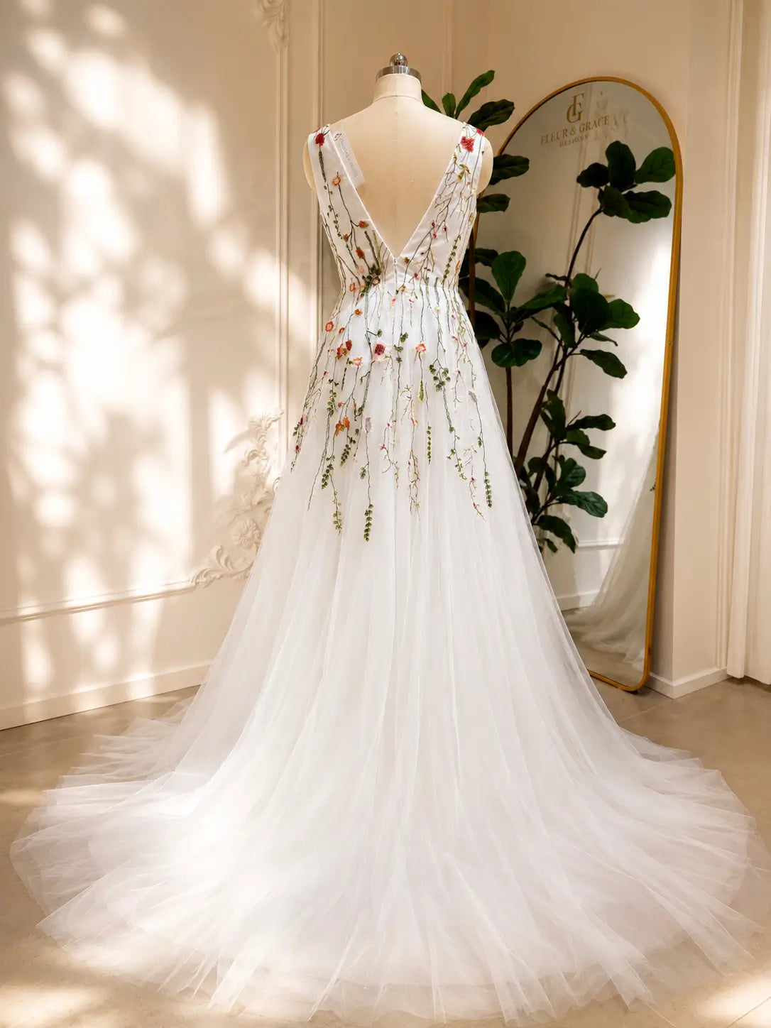 A-line wedding dress with a low V-back, featuring delicate pink and green floral embroidery on flowing white tulle.