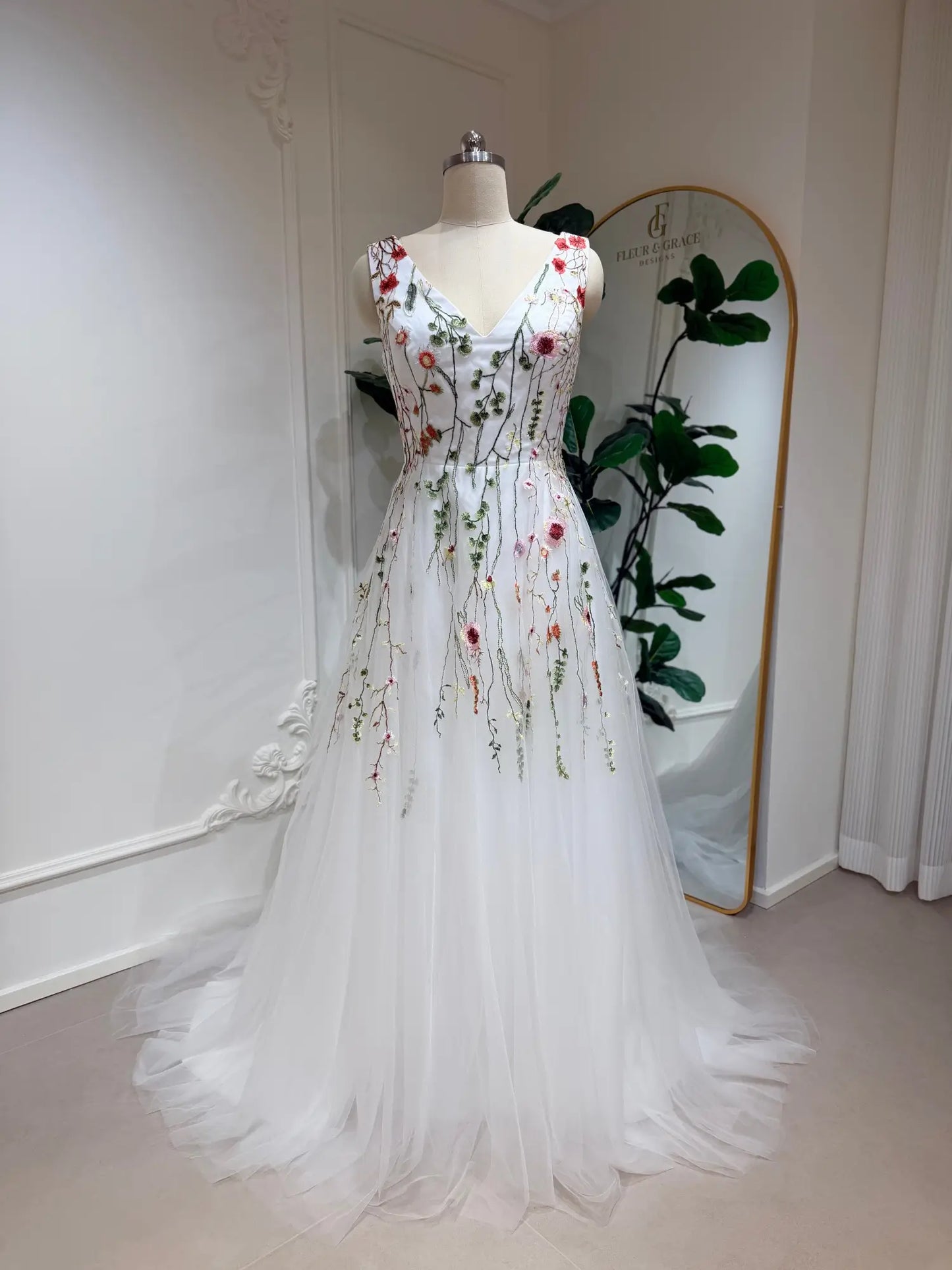 A-line wedding dress with V-neck, featuring colorful botanical embroidery on a flowing white tulle skirt.